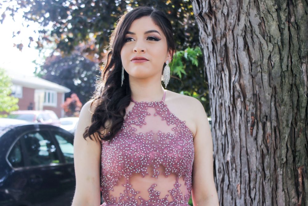 Formal event photos with sparkly pink dress by a tree in natural outdoor lighting.