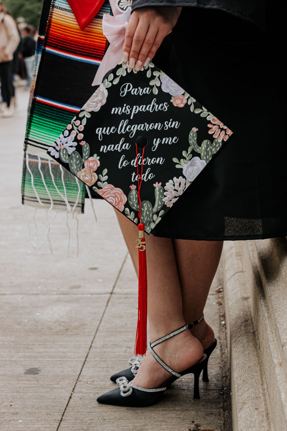 Decorated graduation caps display personalized Spanish messages and colorful designs.