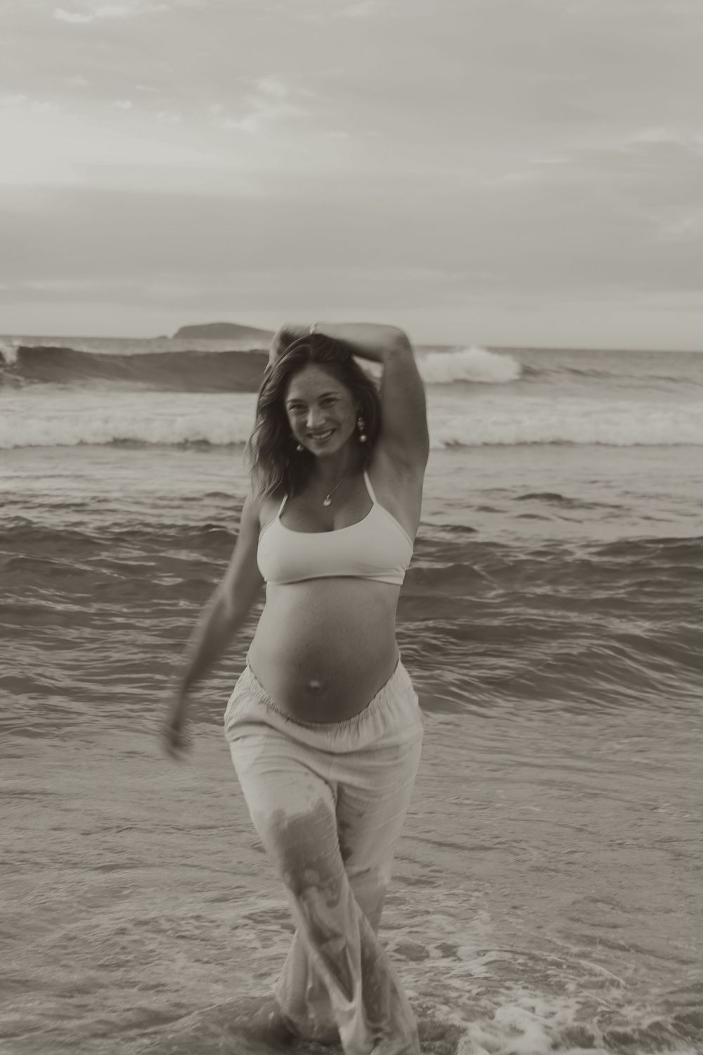 A black and white photo series shows a person joyfully playing and splashing in ocean waves at the beach.