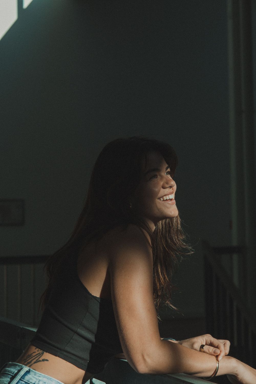 Candid portrait of someone laughing joyfully in moody lighting.