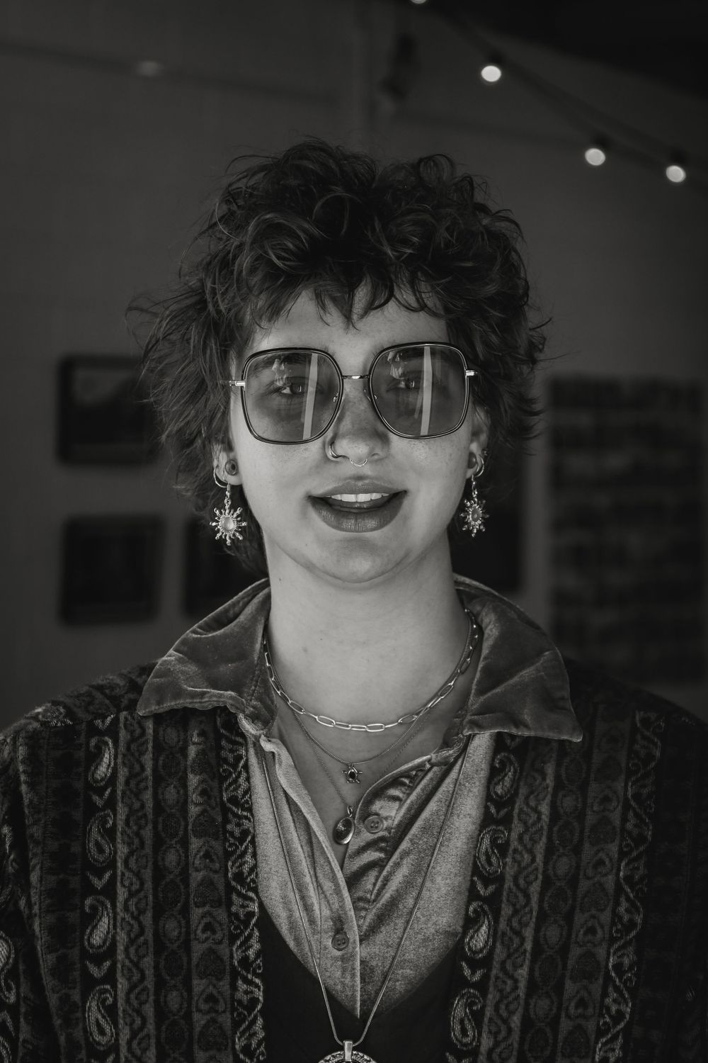 Monochrome portrait shows person in patterned jacket and glasses with vintage styling.