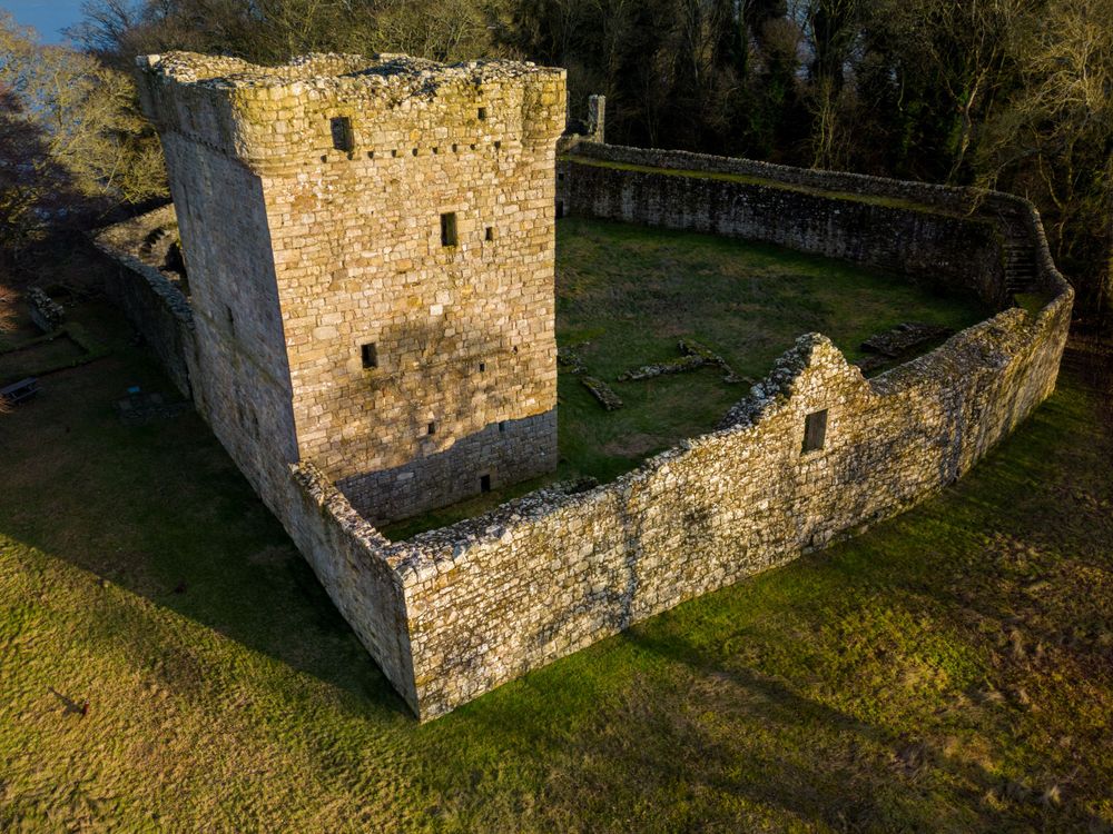 Historic stone building ruins photographed from above showing weathered walls and foundations.