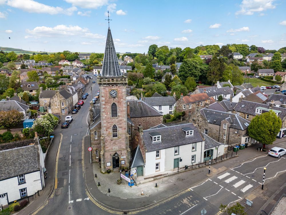 Aerial view of a Scottish village with traditional stone buildings and church spires.