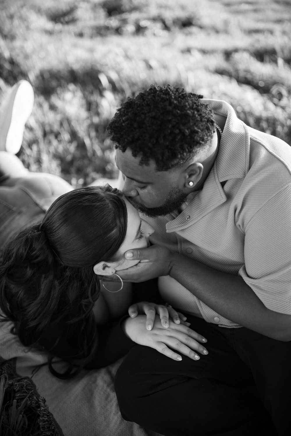 A black and white portrait of a couple sharing an intimate moment outdoors.