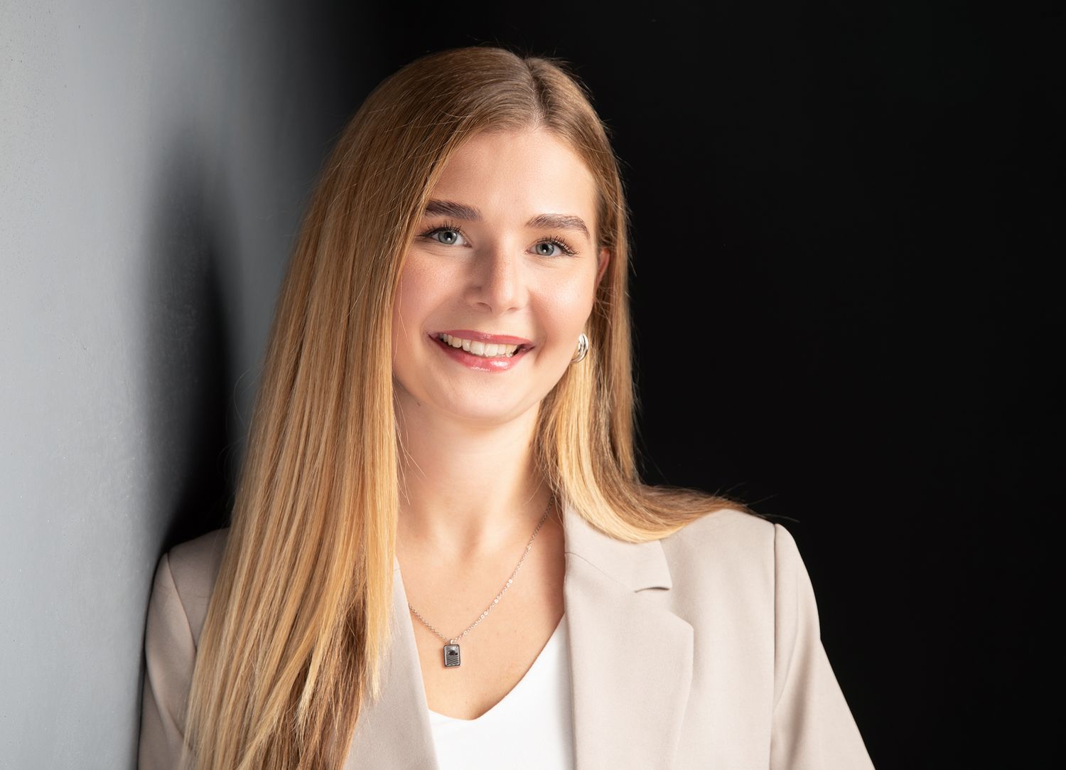 Professionelles bewerbungsfoto einer Frau im Fotostudio vor einem dunklen Hintergrund.	Tipps Kleidung Bewerbungsfoto Frauen