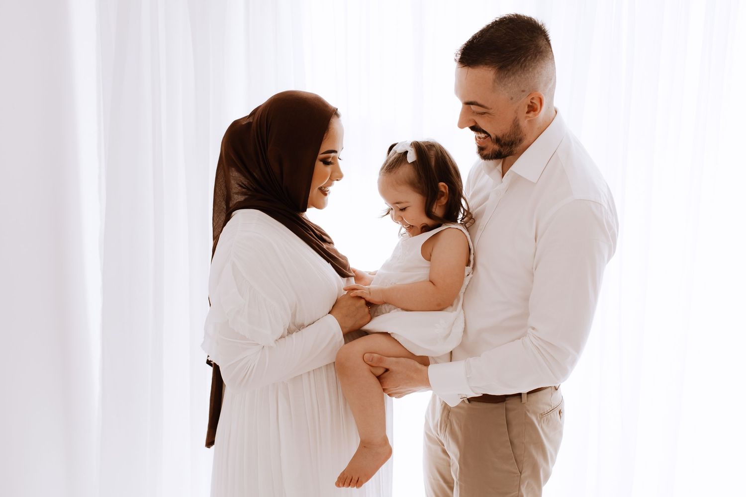 Family portrait session in white studio with soft lighting and tender moments.