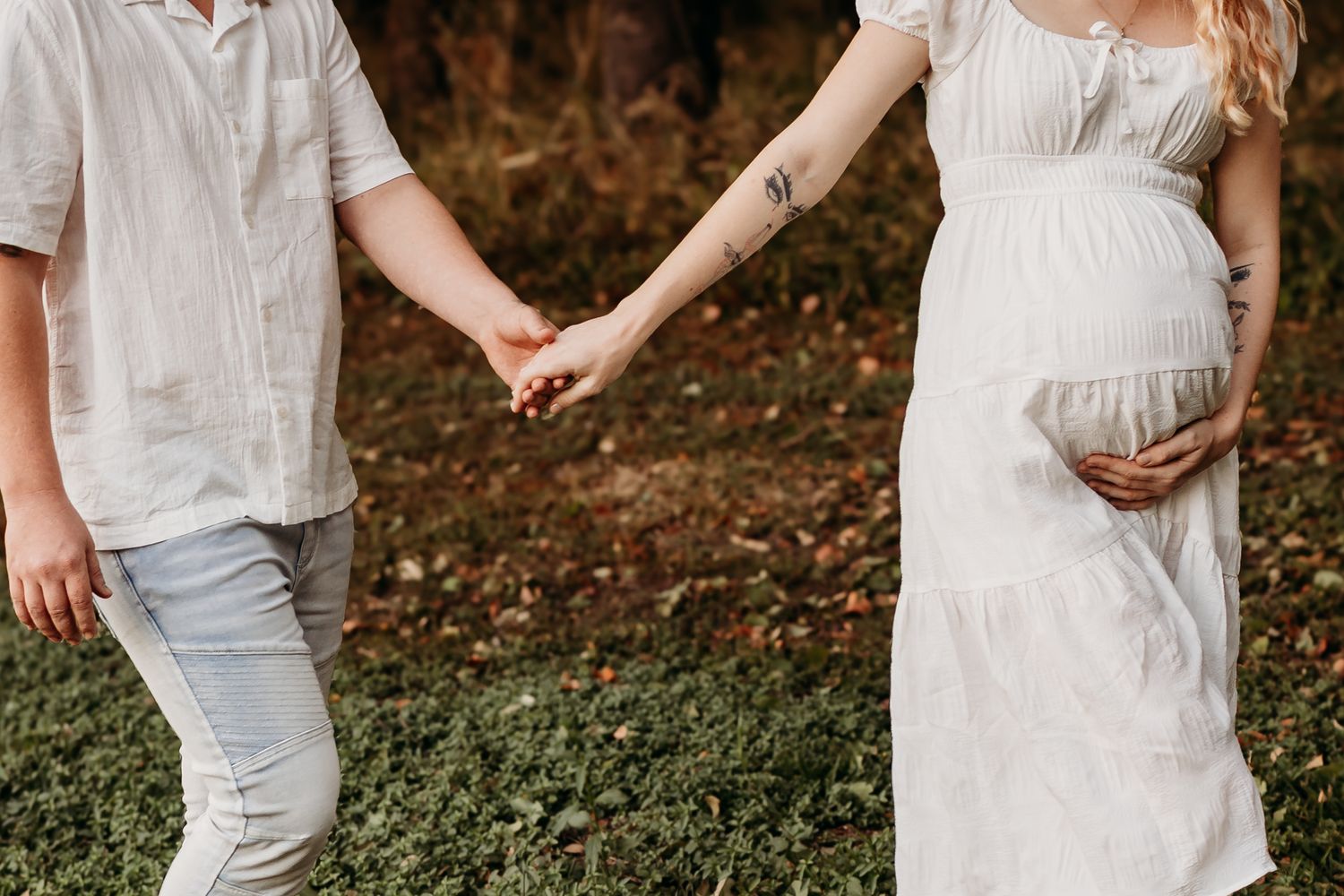 Maternity photoshoot in a natural outdoor setting with soft autumn colors and white clothing.