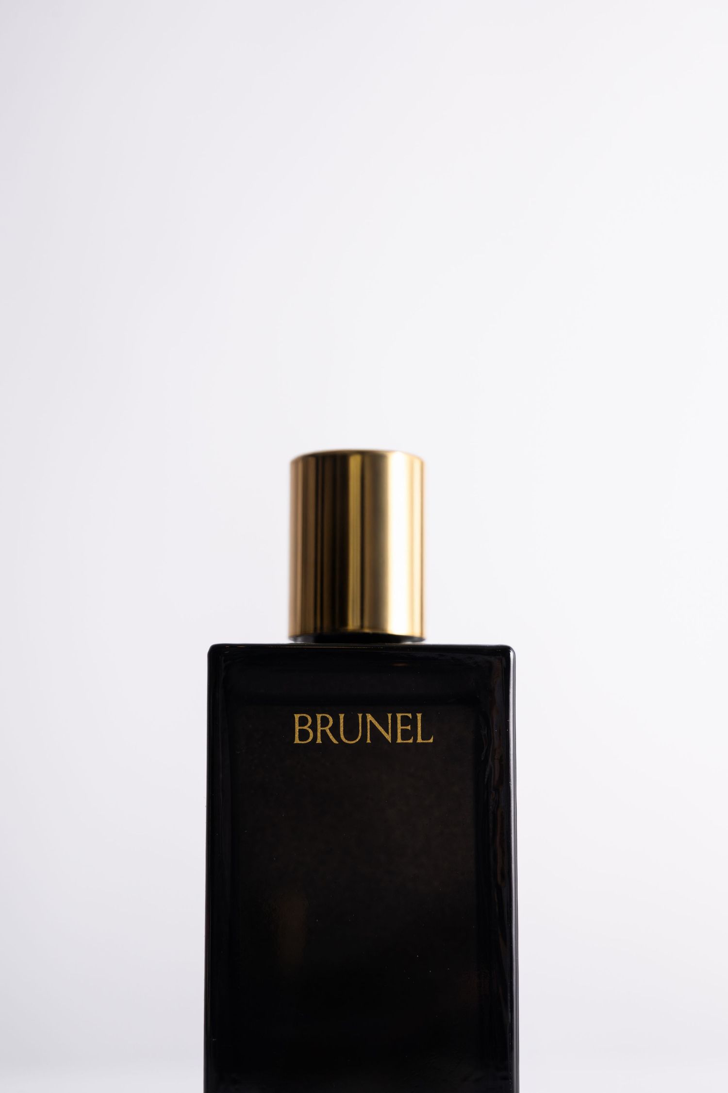 Brunel black rectangular perfume bottle with gold cap on white background.