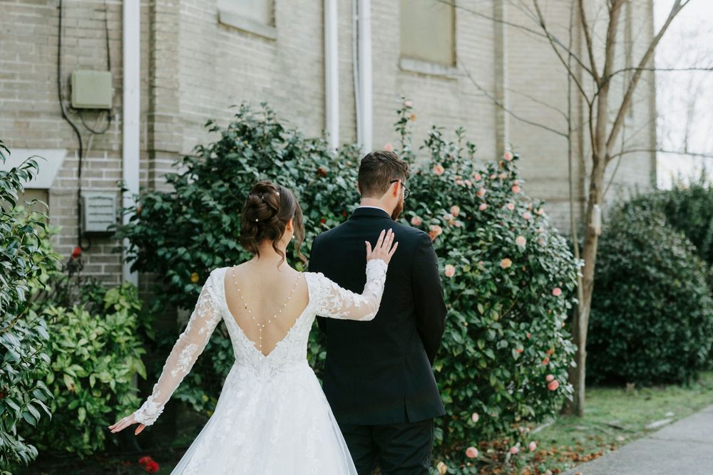 Newlywed couple walks together through a garden path during an outdoor wedding photo session.