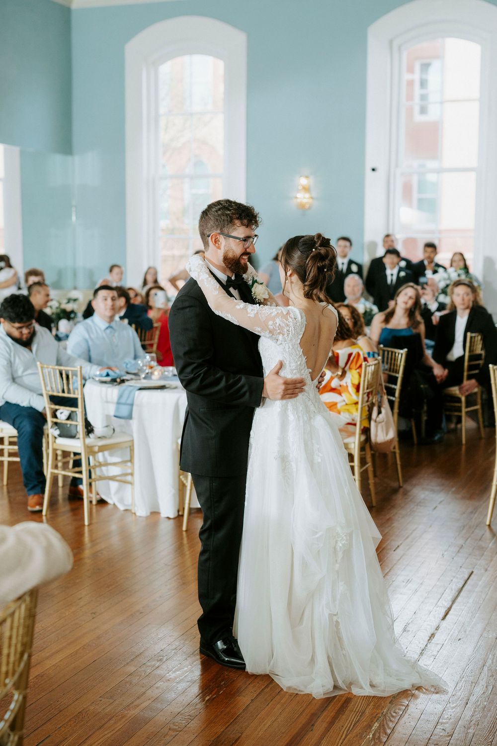 Wedding reception in a bright turquoise ballroom with couples dancing on hardwood floors.