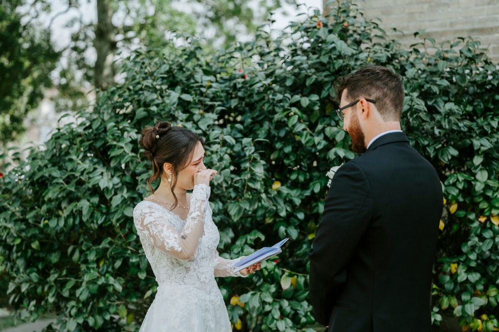 A couple shares a romantic moment in front of an ivy-covered wall during their wedding photoshoot.