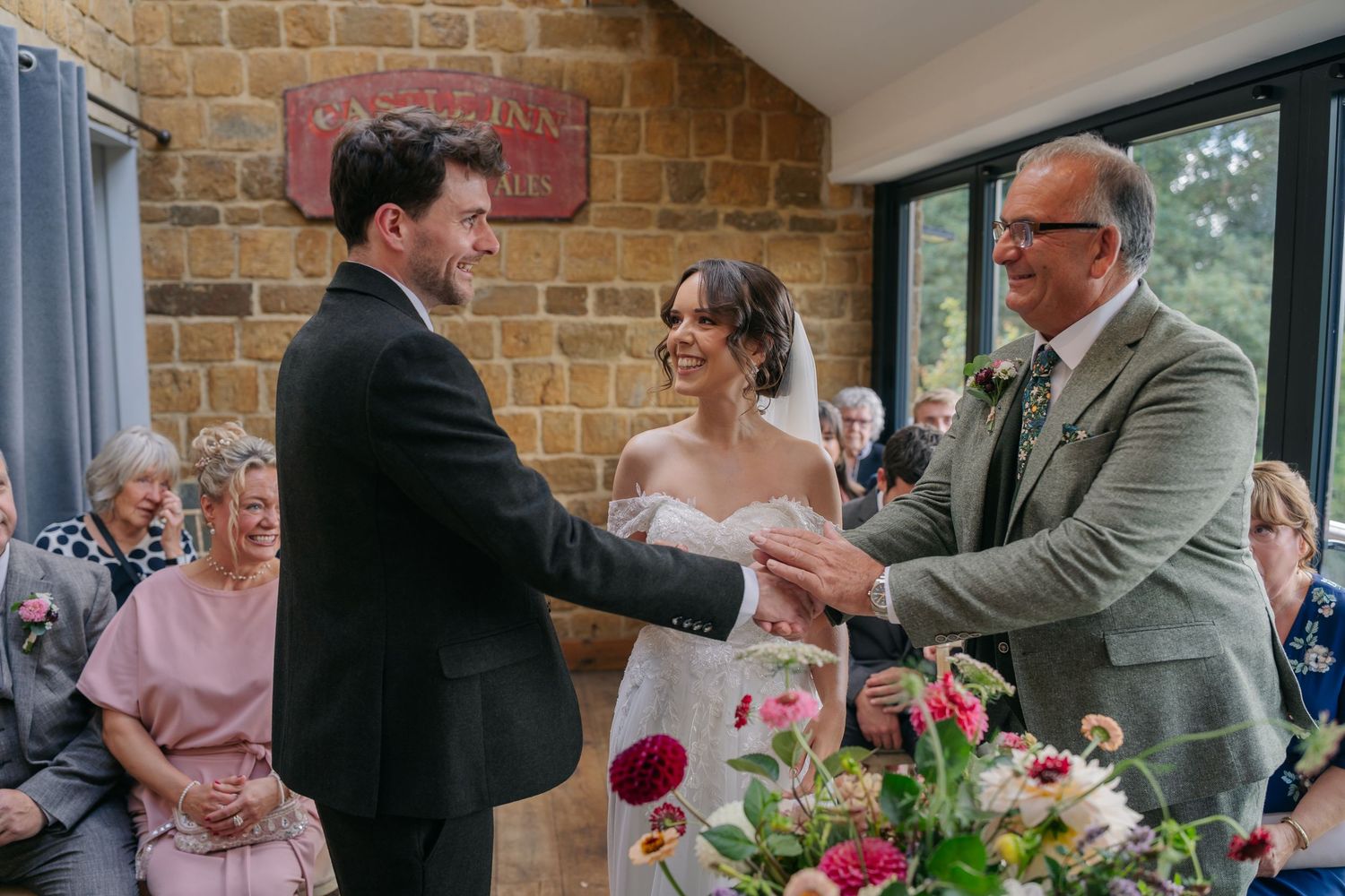Wedding guests mingle and socialize during an outdoor reception at a rustic brick venue with floral decorations.