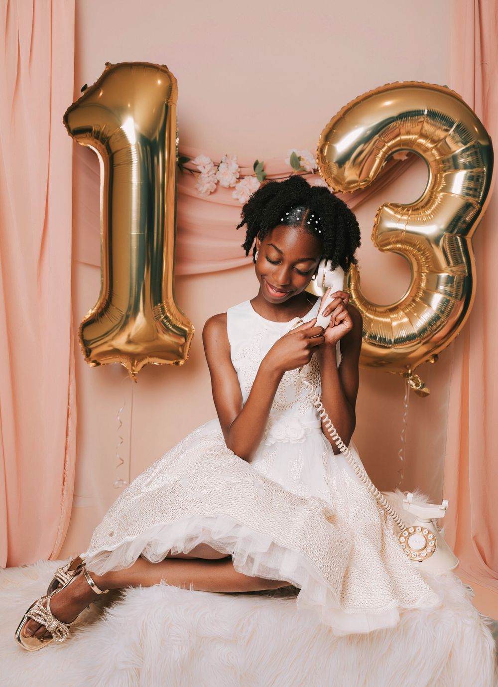 A series of photos showing a young girl in a white dress posing against a pink backdrop with gold 13 number balloons.