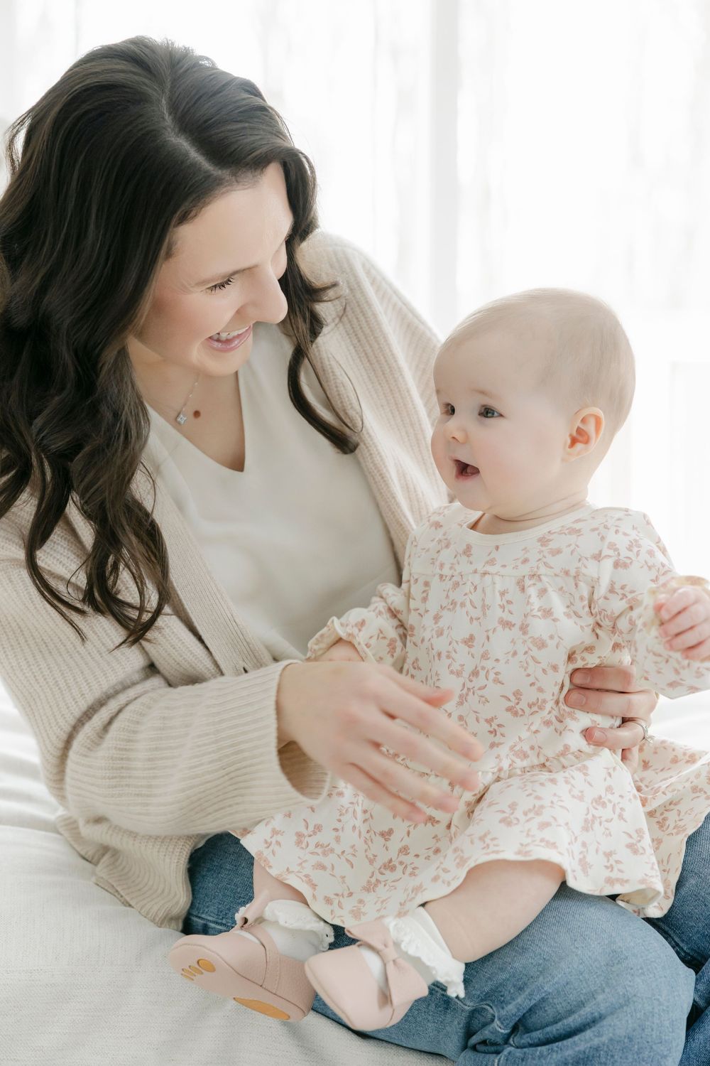 A tender moment between parent and baby wearing a floral dress while sitting together in casual attire.