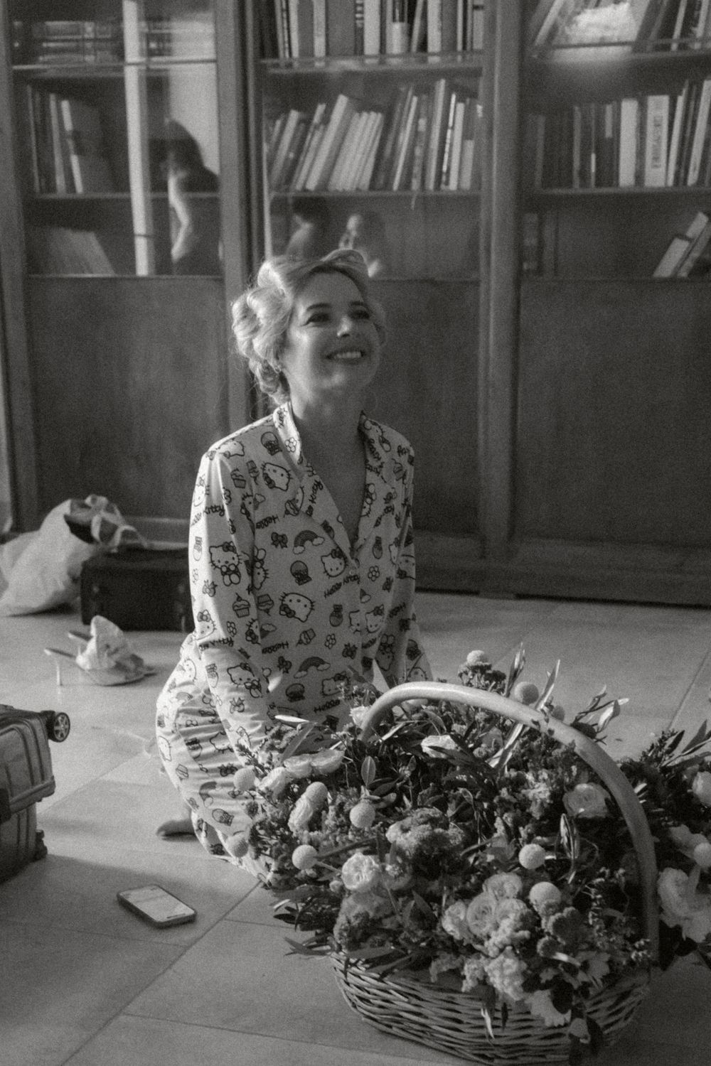 A person sits at a table with a large spread of food and bookshelves visible in the background.