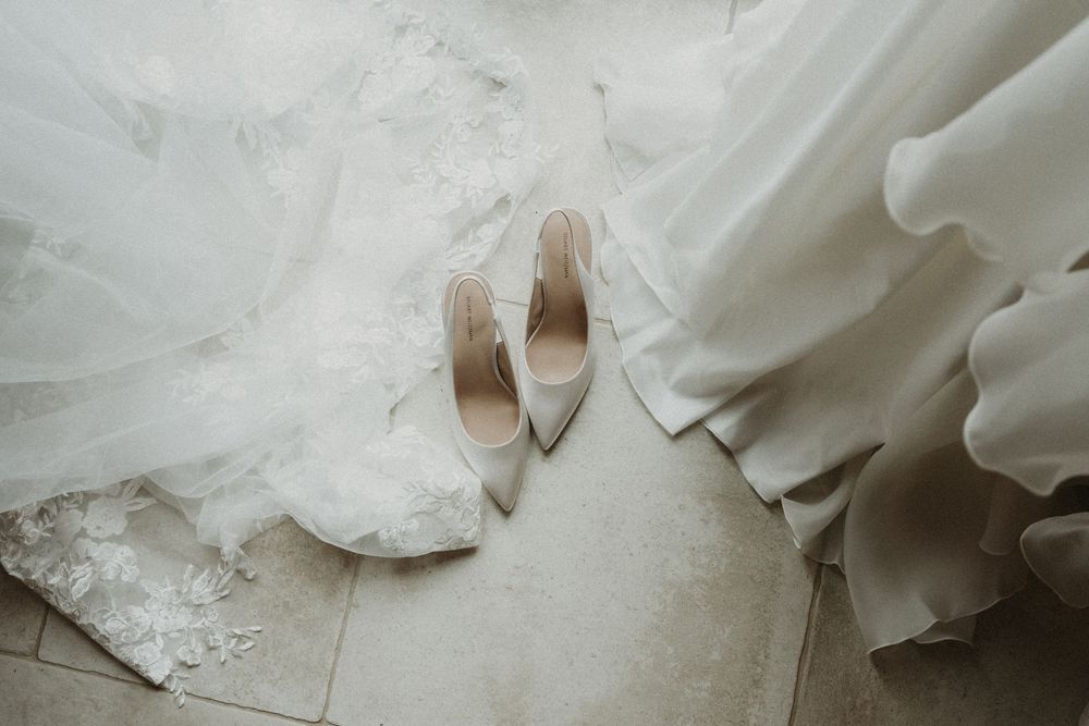 A collection of wedding dress details showing delicate lace, tulle fabric, and elegant beading in soft white tones.