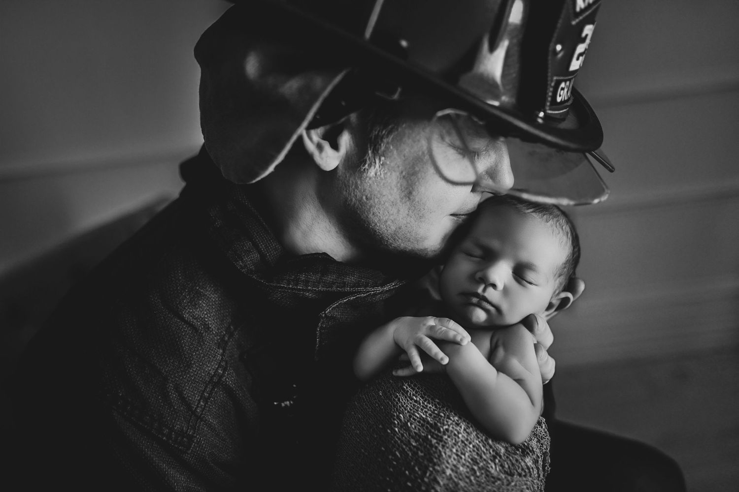 Firefighter parents holding their newborn during a luxury studio newborn session in Denton, Texas with soft natural light