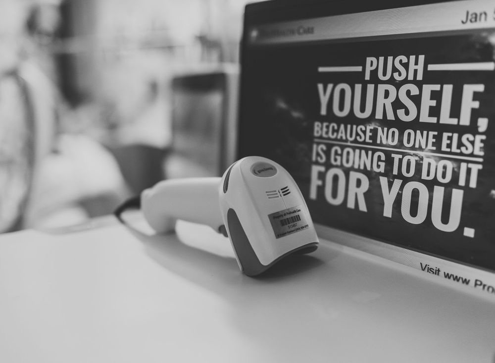 A black and white image shows a row of motivational text signs mounted on a wall with inspirational messages.