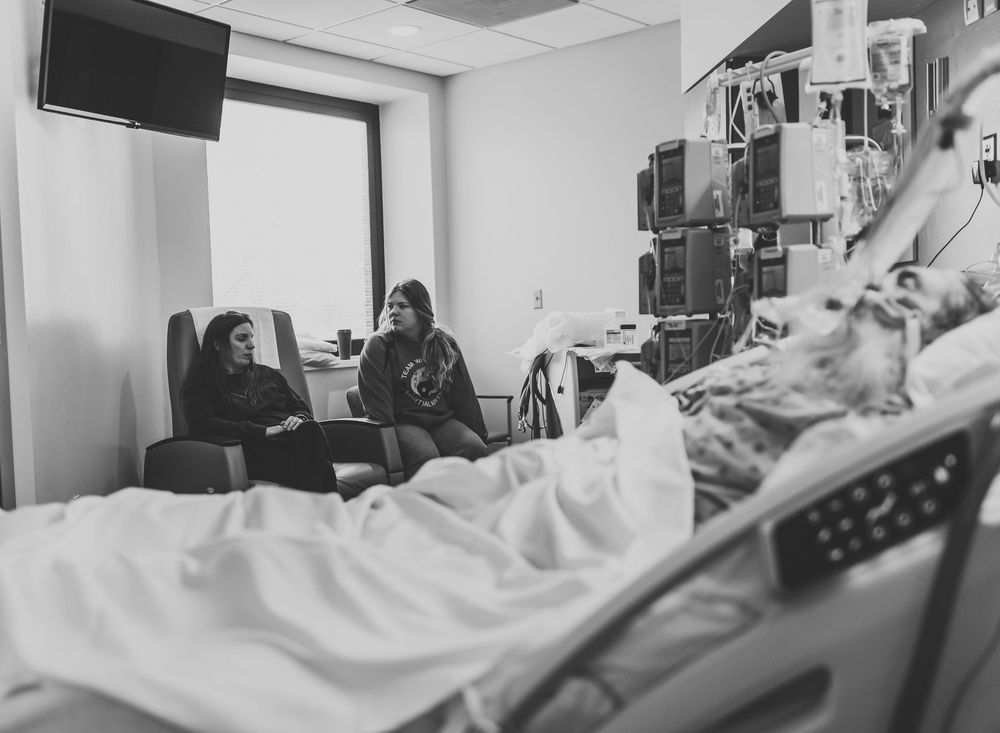 Black and white photo of patients receiving medical care in a hospital ward with medical equipment visible.