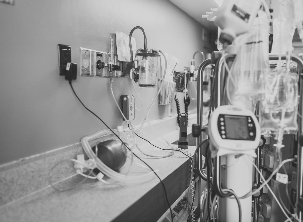Medical equipment and monitors in a hospital intensive care unit showing vital signs and patient data.
