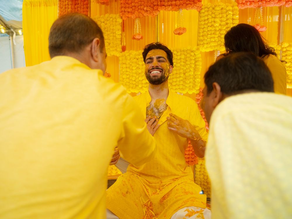 People celebrate at a vibrant Indian wedding ceremony with traditional yellow decorations and attire.
