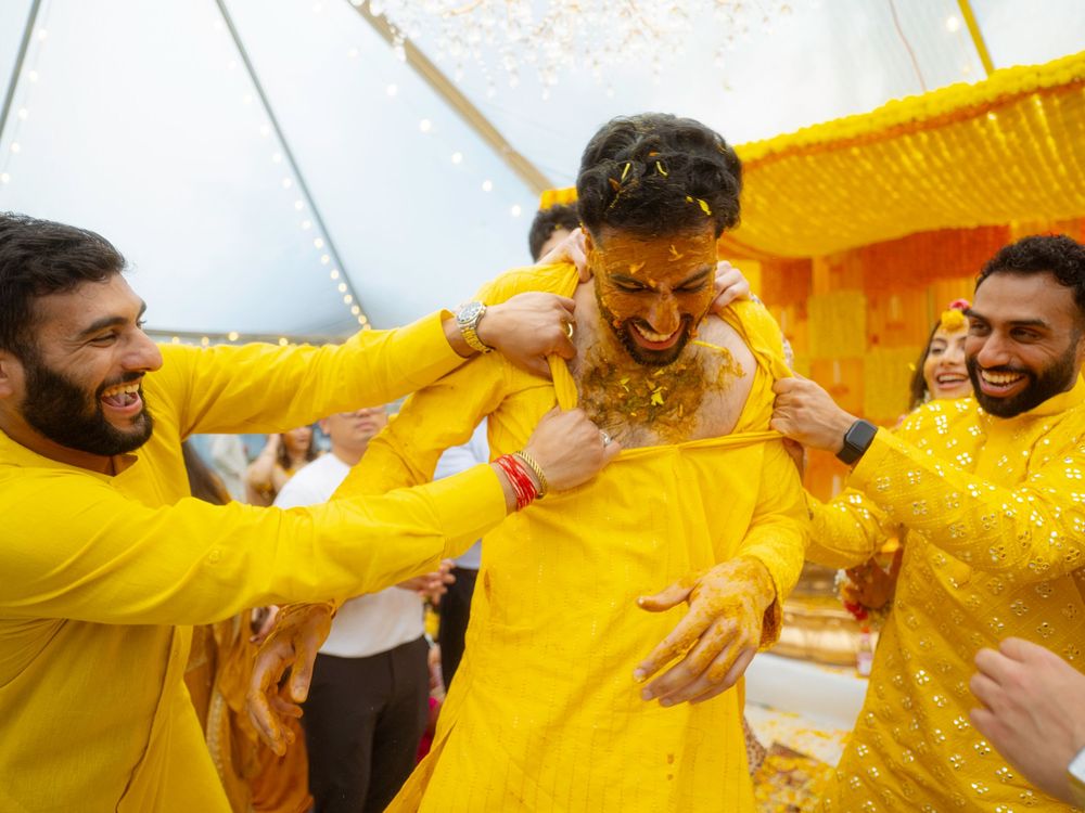 Joyful celebration at an Indian wedding with guests wearing bright yellow traditional attire during the haldi ceremony.