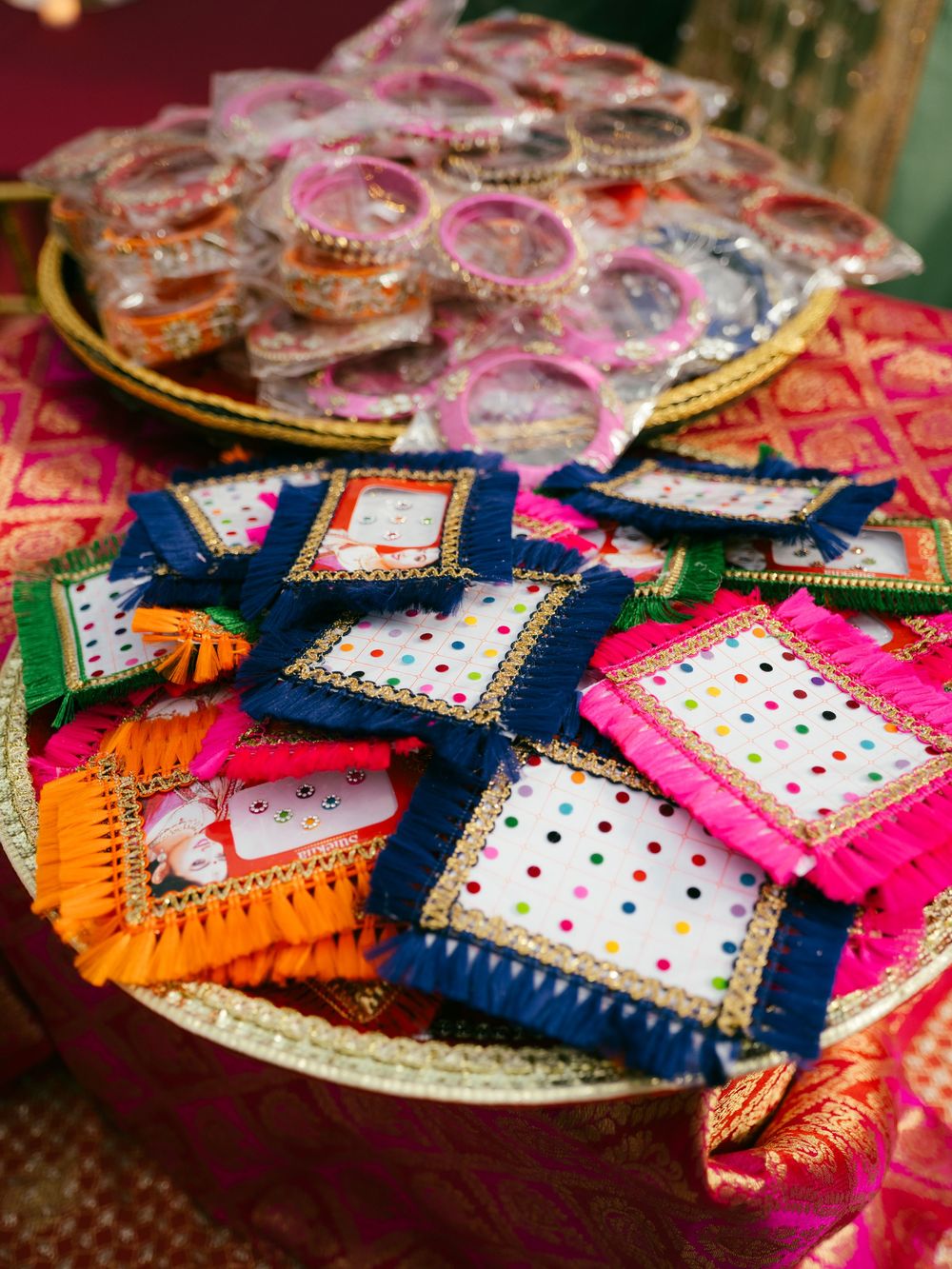 Colorful traditional Indian wedding favors with intricate embroidery and mirror work displayed on decorative plates.
