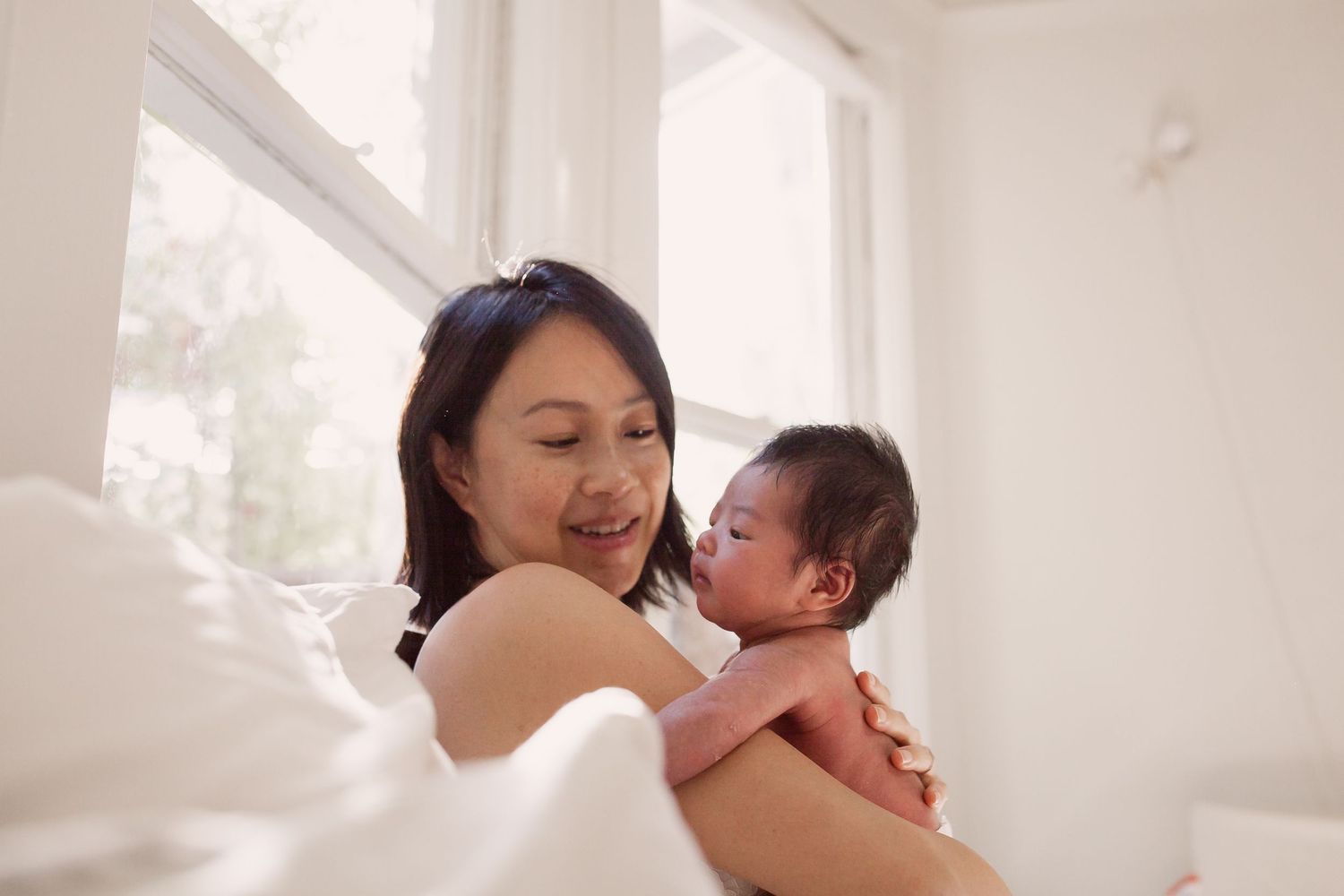 In-home newborn mini session in San Anselmo, Marin County. A tender moment between parent and baby in a bright, sunlit room.