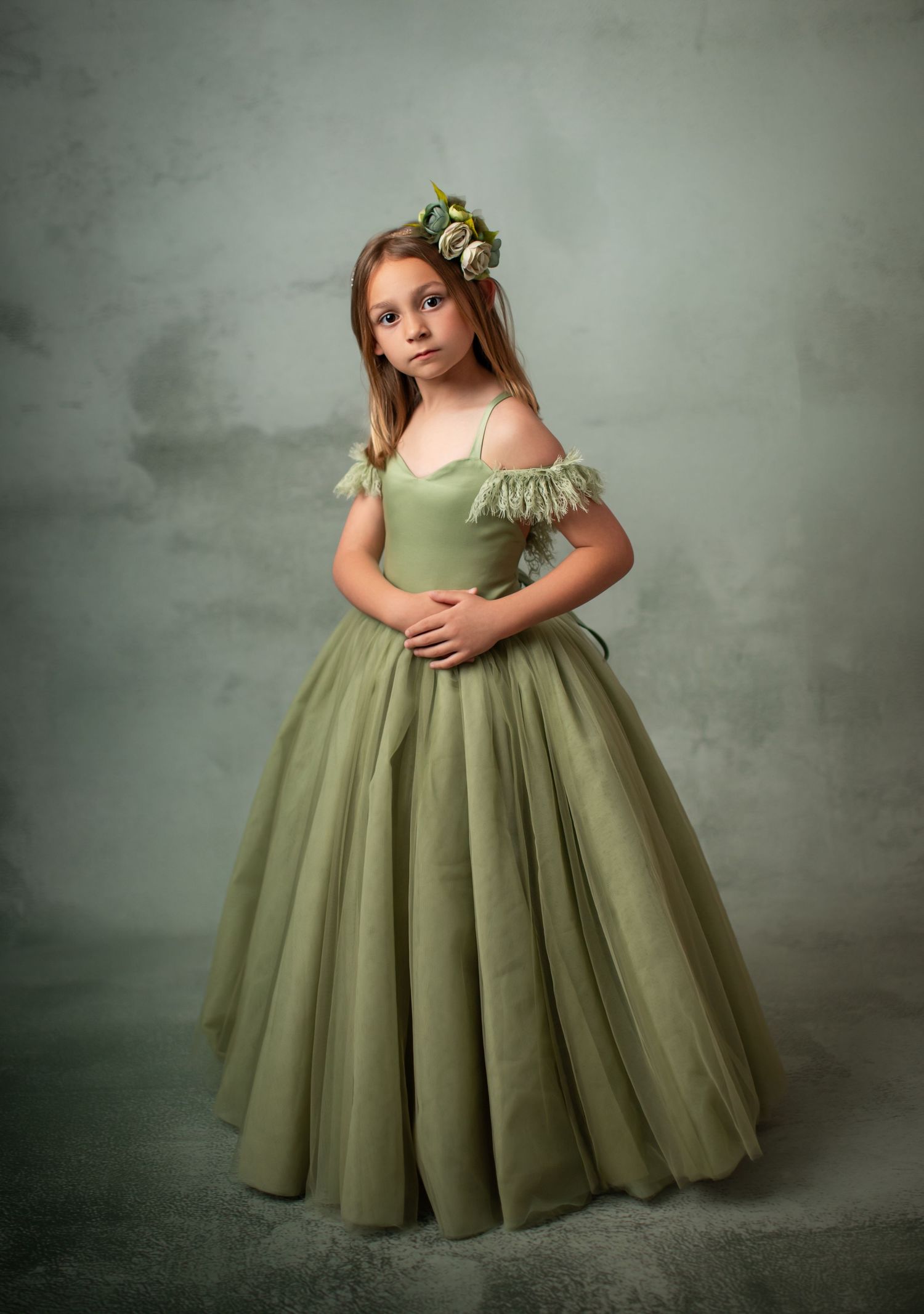 Elegant olive green ballgown with layered tulle skirt in dreamy studio portrait setting.