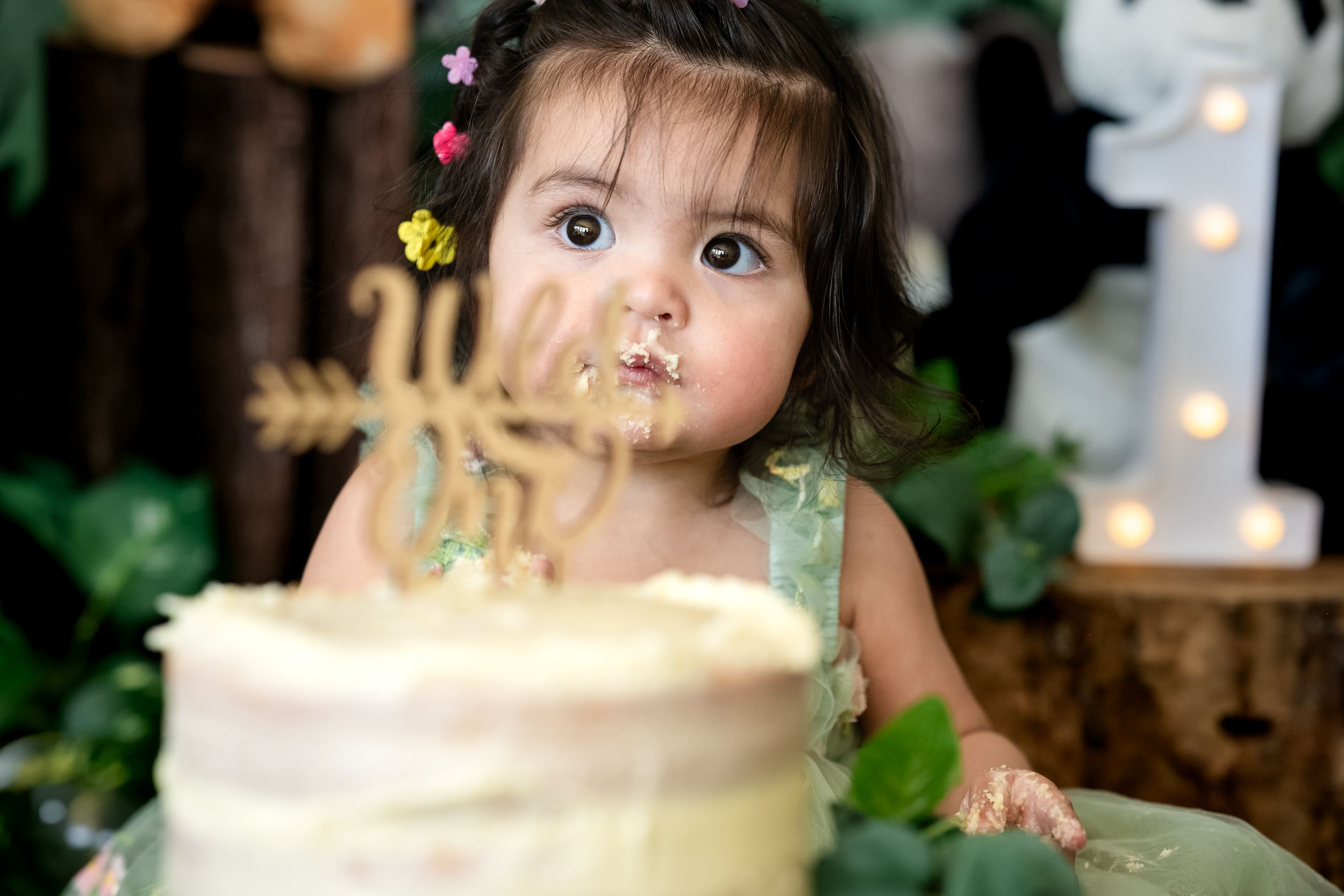 A child leans over a birthday cake with lit candles while celebrating at a festive party.