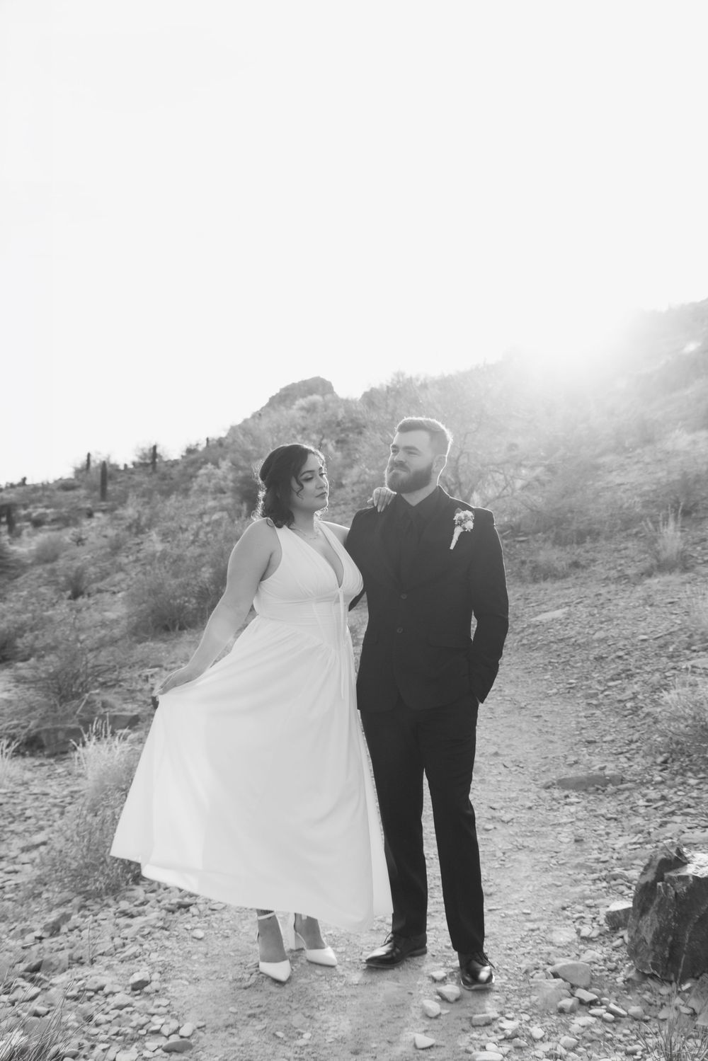 A black and white photo series of a couple in wedding attire posing together on a rocky mountainside path.