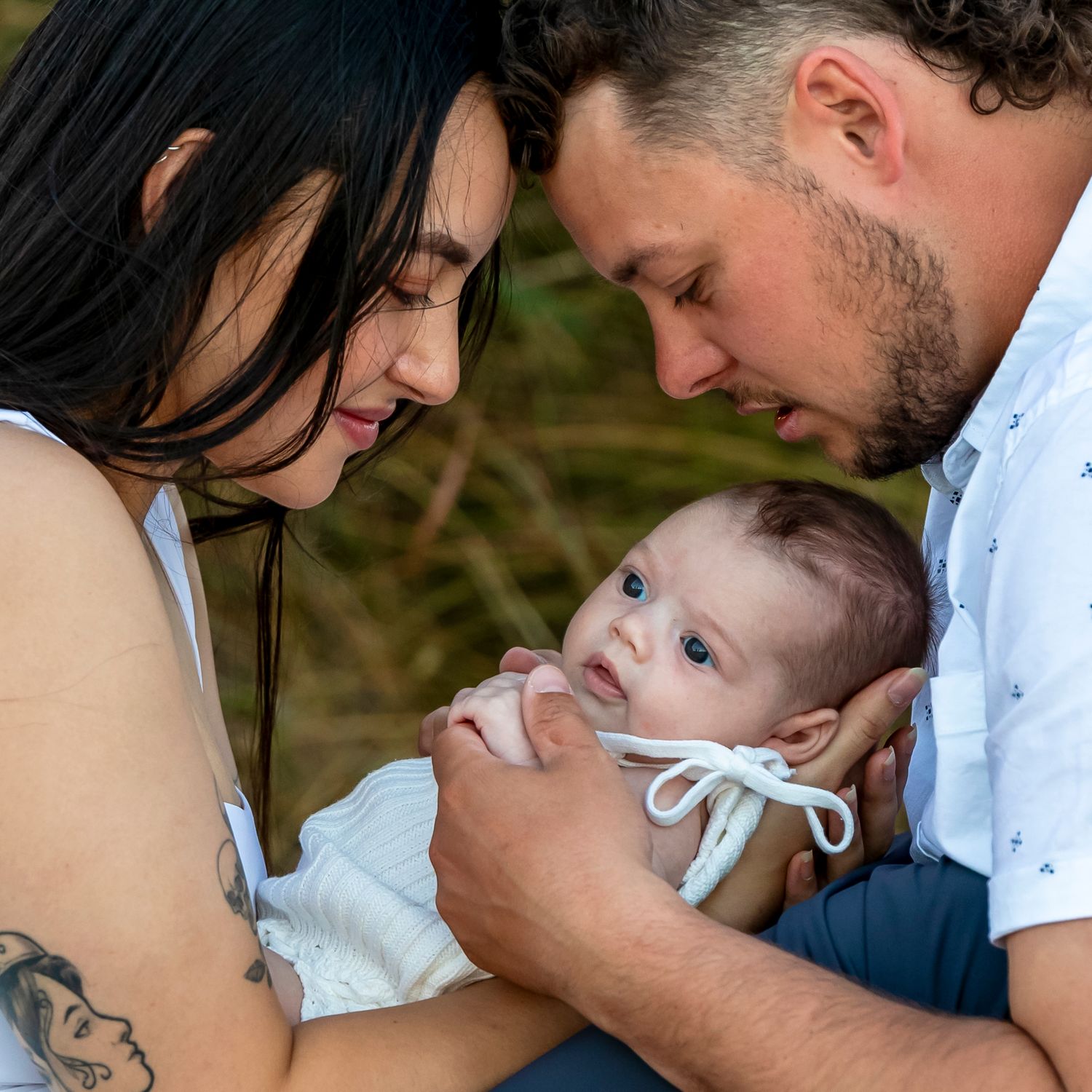 Parents holding baby during a relaxed outdoor session in Perth.