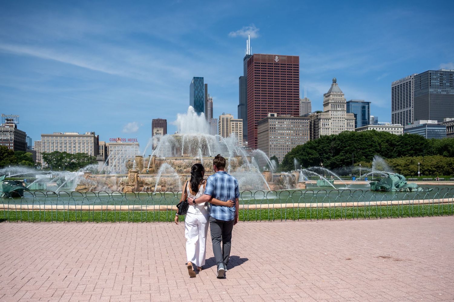 Chicago skyline panorama with Buckingham Fountain and skyscrapers reflecting in Lake Michigan on a sunny day.