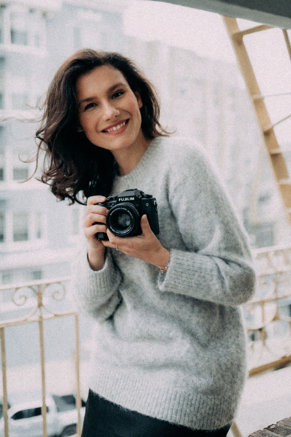 Portrait of person in casual grey t-shirt with messy bun hairstyle against white background.