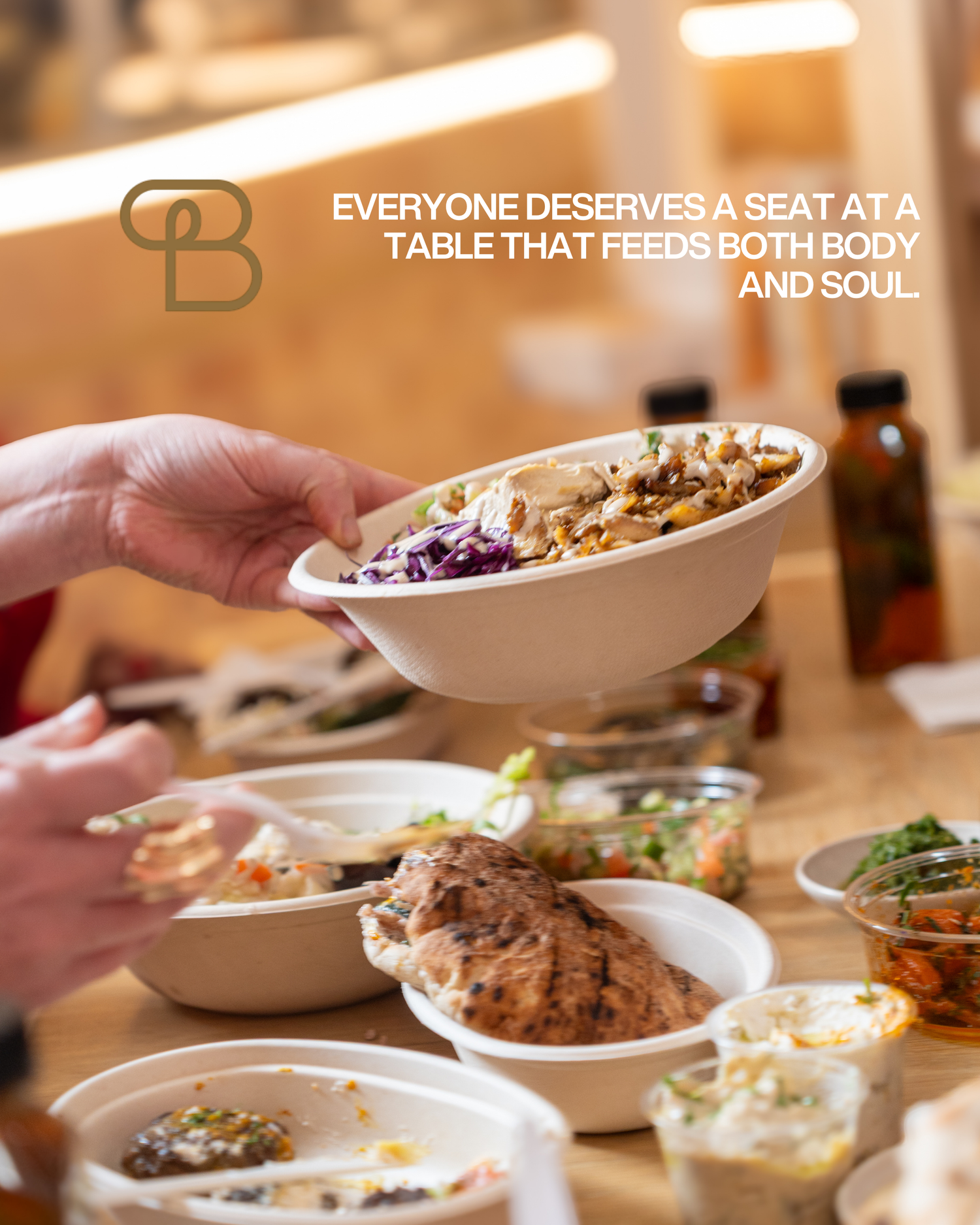 Hand holding a bowl of grain salad over a table filled with Middle Eastern dishes at a restaurant.