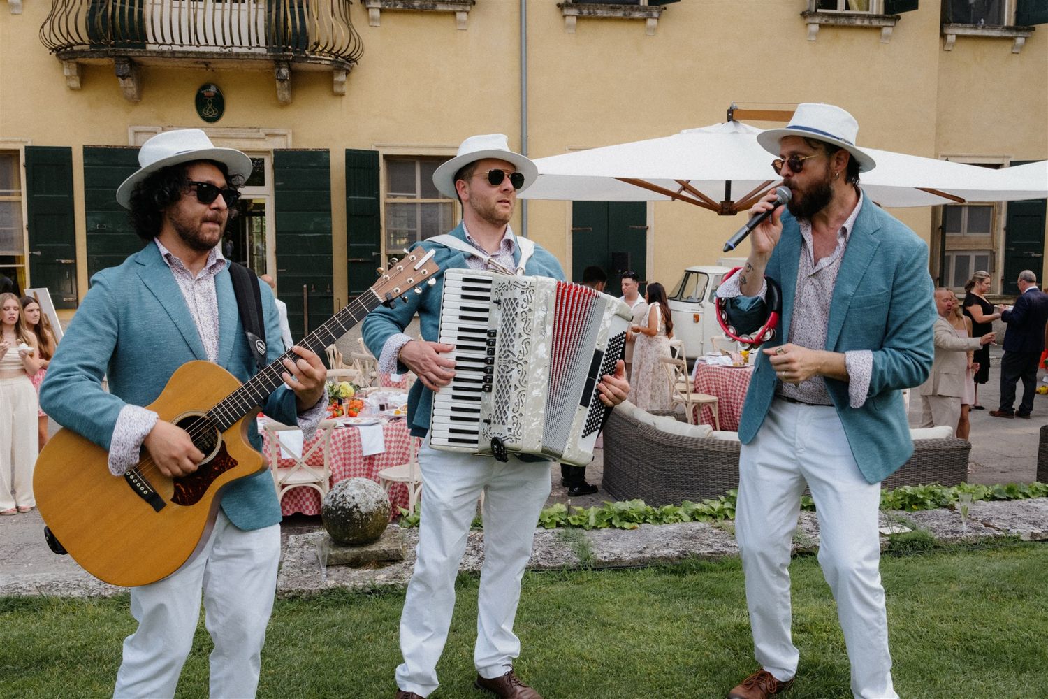 Bride and groom walking in the gardens of Isola del Garda accompanied by a roaming band