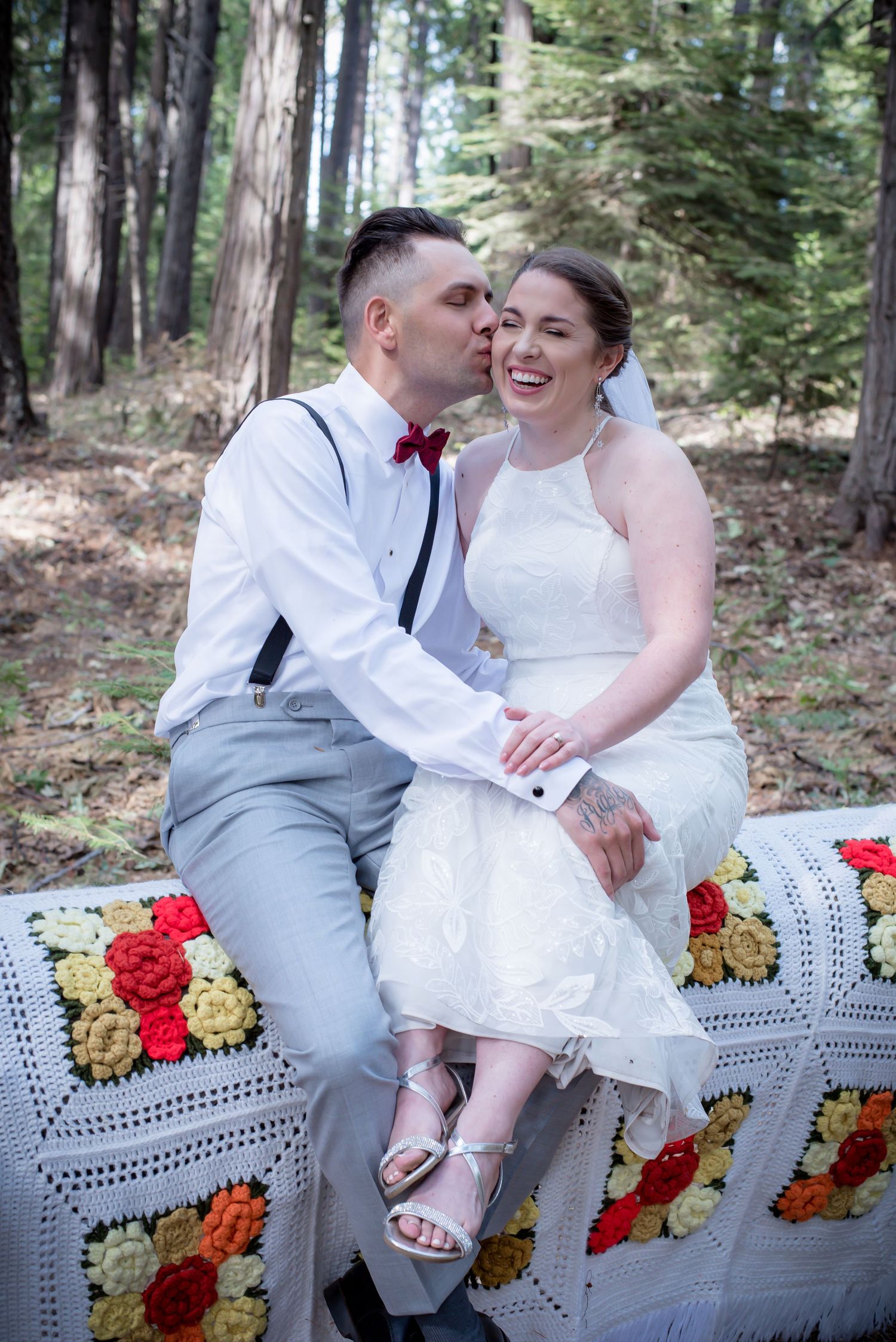 Portrait of bride laughing while groom kissing her on the cheek. Photo by Ashley Nicole Baeza - Caffeinated Candids Photography.