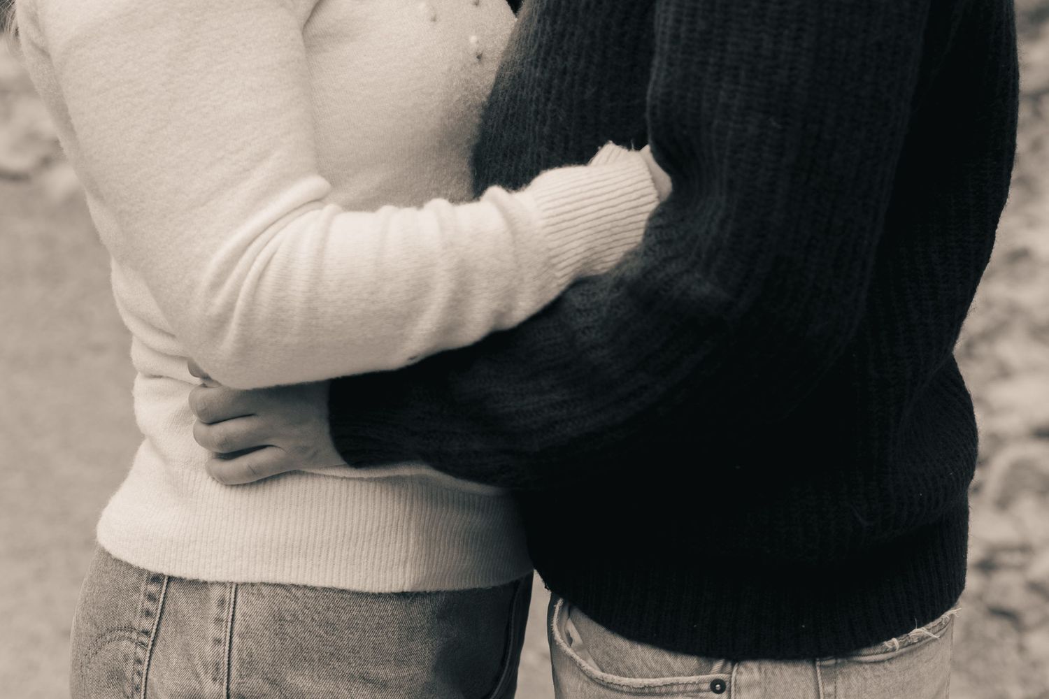 Black and white close-up of couple embracing, wearing casual white and dark knit sweaters.