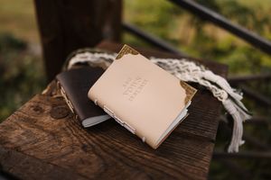 A leather wallet sits on rustic wooden surface in natural outdoor lighting.