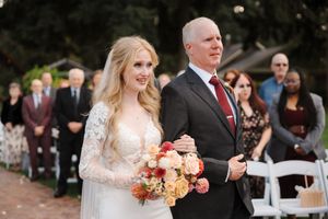 Bride and groom exchange vows during an outdoor garden wedding ceremony surrounded by guests.