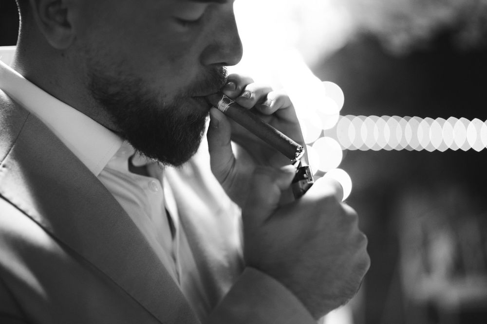 Groom lighting a cigar during the evening party at Villa Nobel Sanremo.