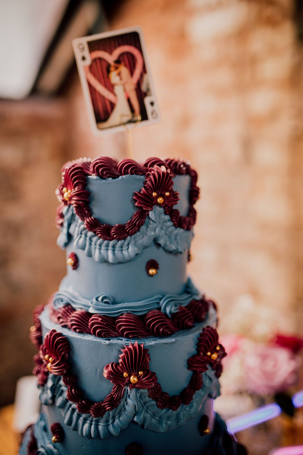 Dark blue wedding cake decorated with burgundy piped details and intricate floral patterns showcases elegant tiered design.
