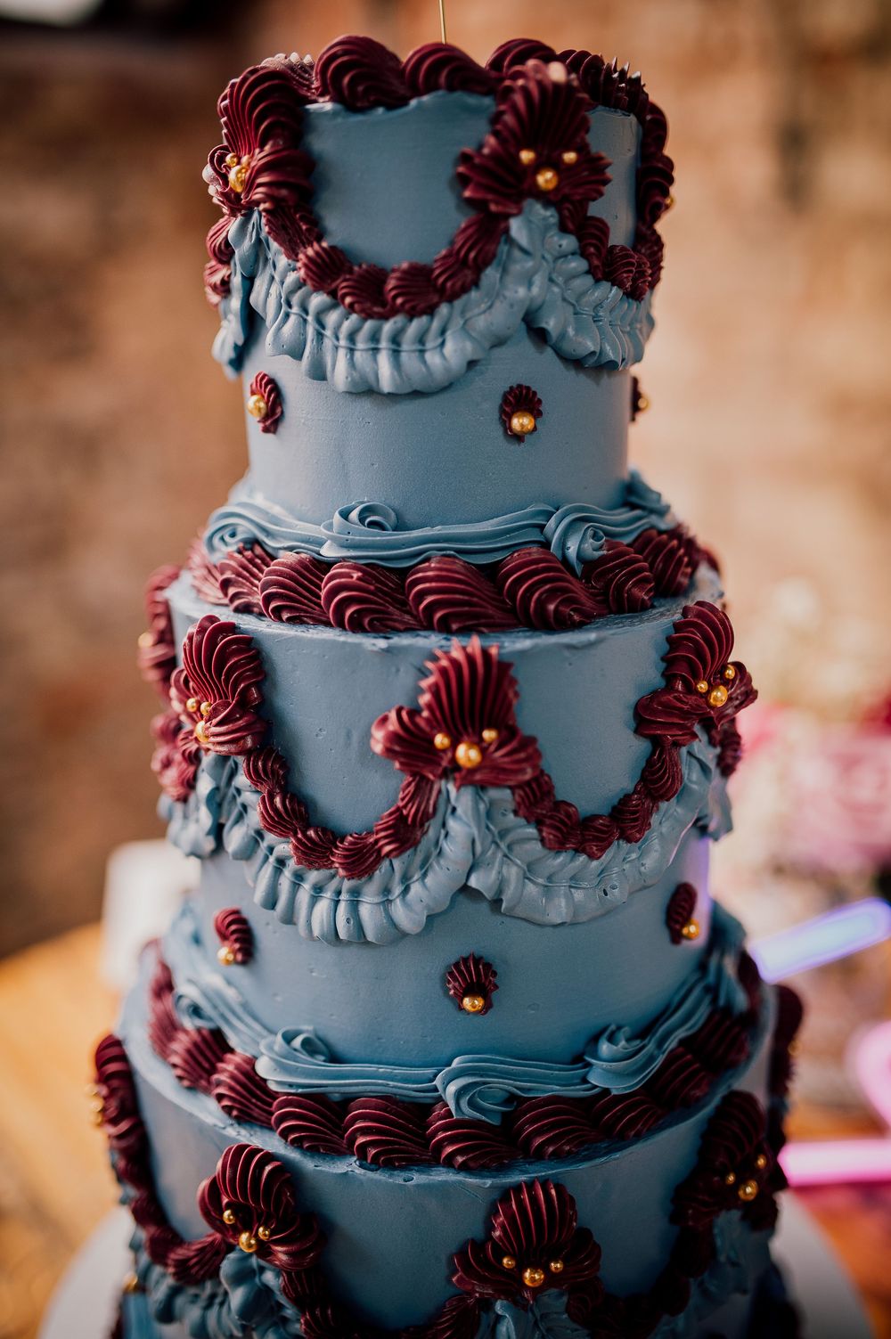 A gothic-style wedding cake decorated with dark gray frosting and deep burgundy piped details creates a dramatic tiered design.