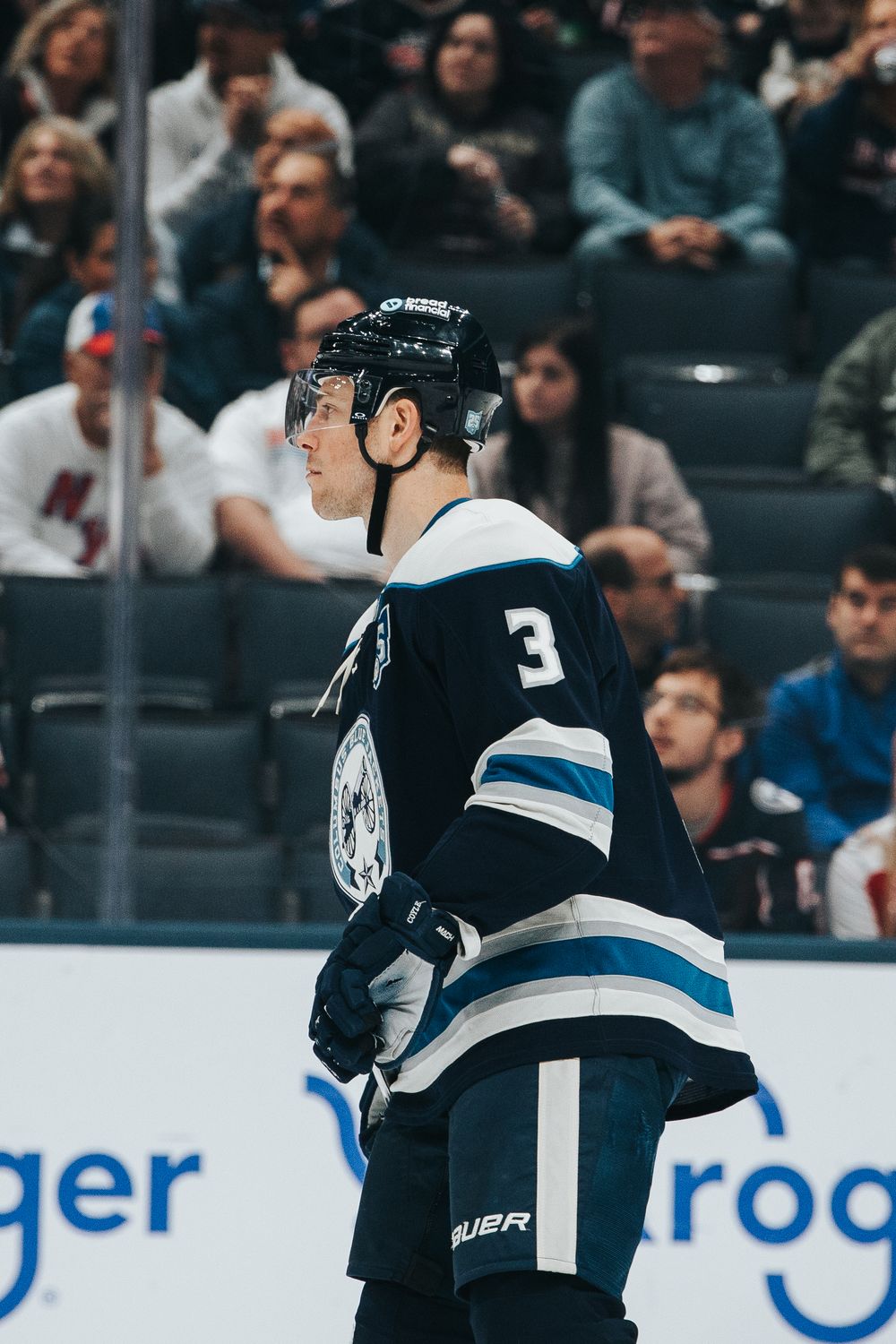 Hockey player in black and white uniform skating on ice during professional game.