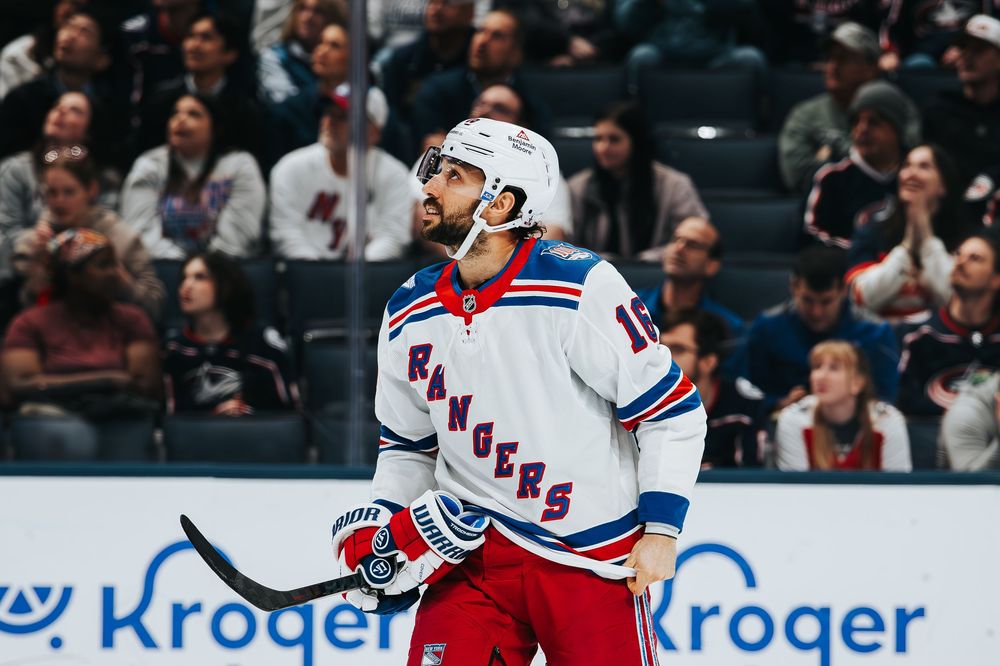 NHL hockey player in white New York Rangers jersey celebrates after scoring a goal during game against opponent.