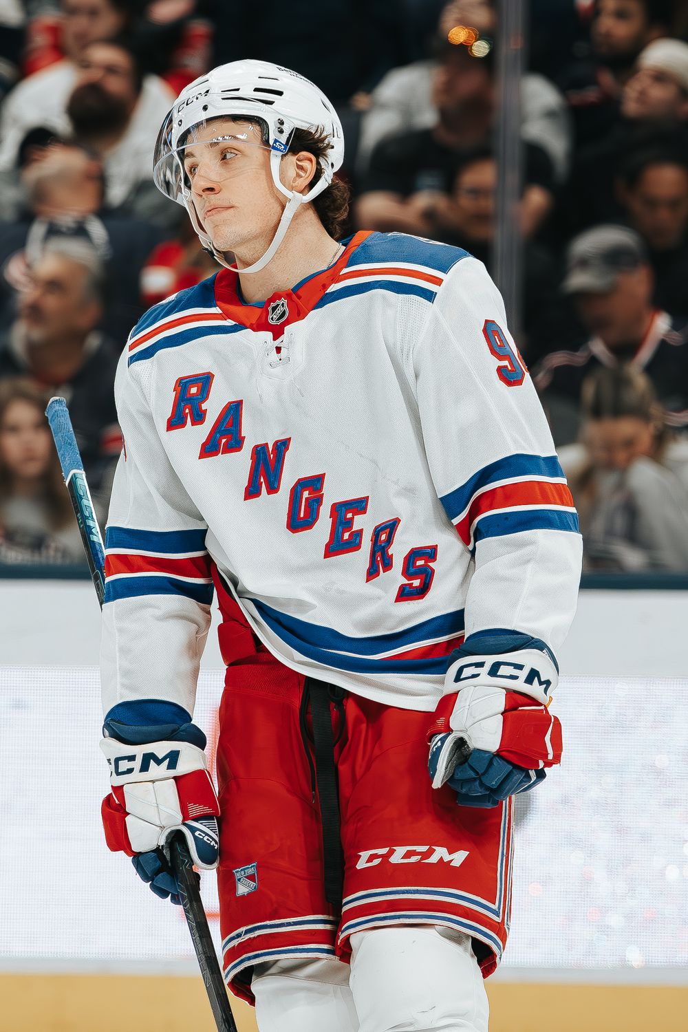 New York Rangers hockey players in white jerseys with red and blue trim skating on ice during NHL game.