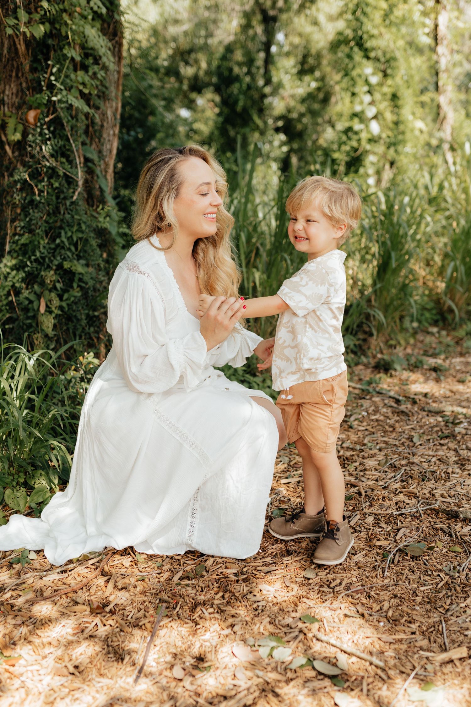 Lifestyle family portrait of a mother and her young child sharing a sweet moment surrounded by natural greenery.