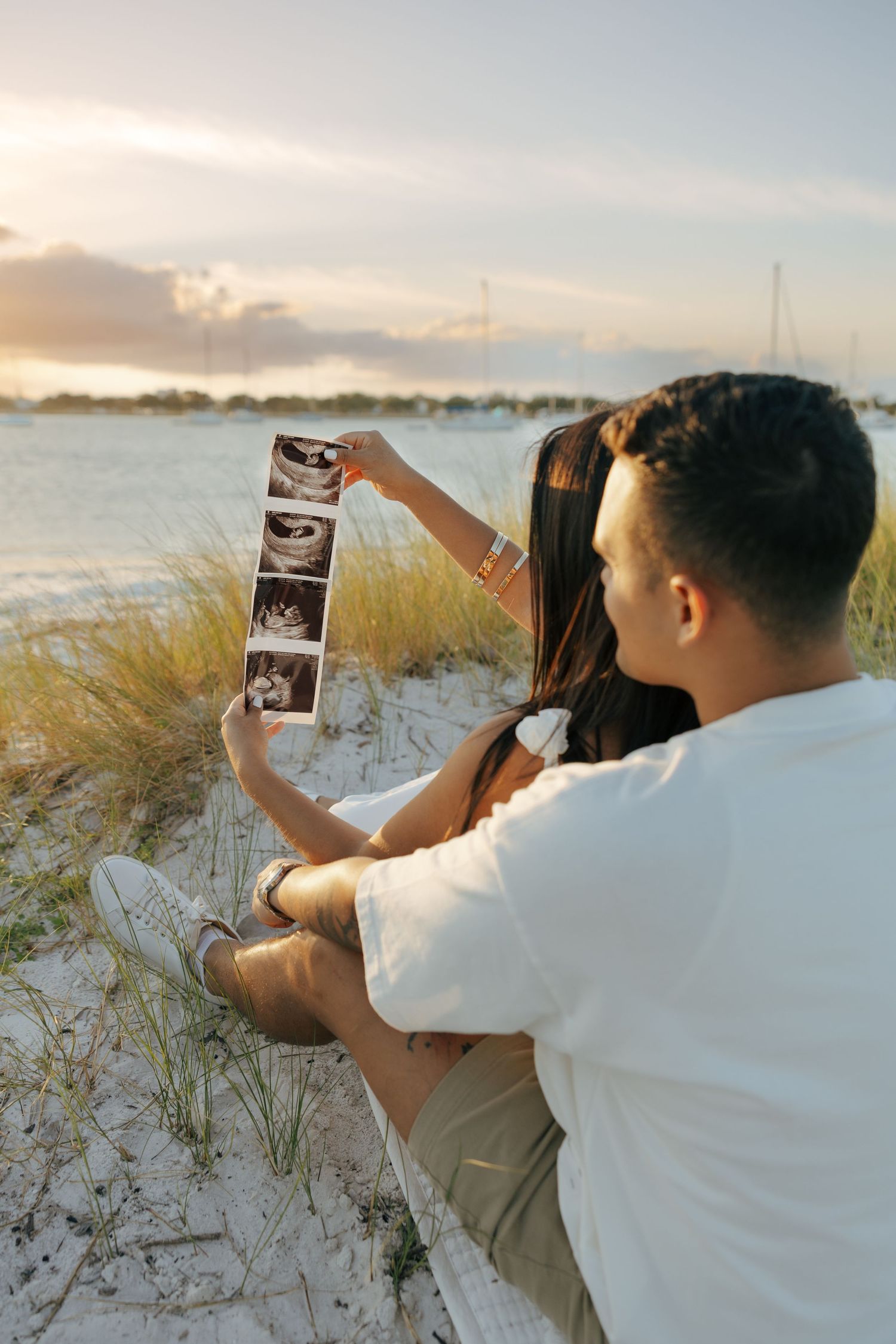 Lifestyle couple session capturing a candid moment of a couple photographing the sunset by the water.