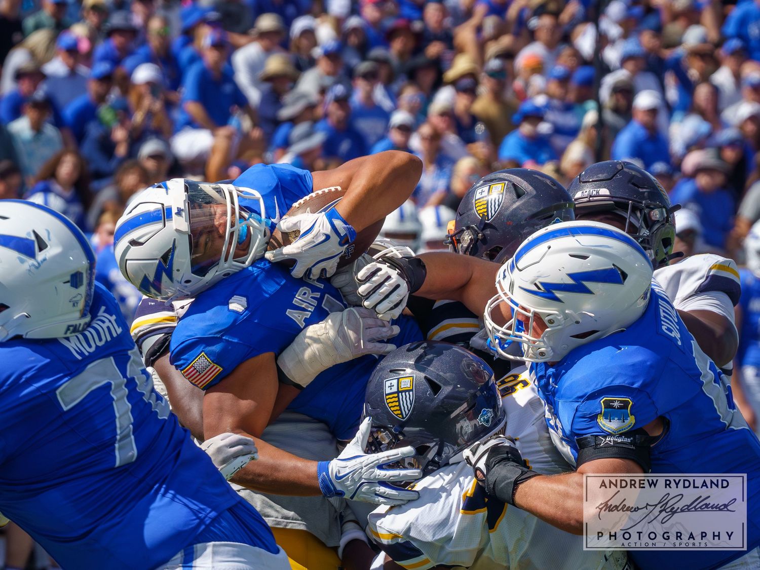 Football players from opposing teams clash in an intense goal-line formation play.