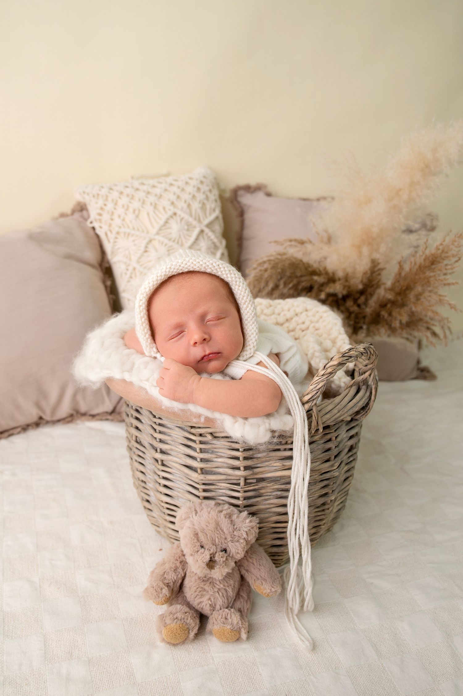 Sleeping newborn baby wrapped in teal swaddle inside wooden bowl surrounded by medical syringes on green background.